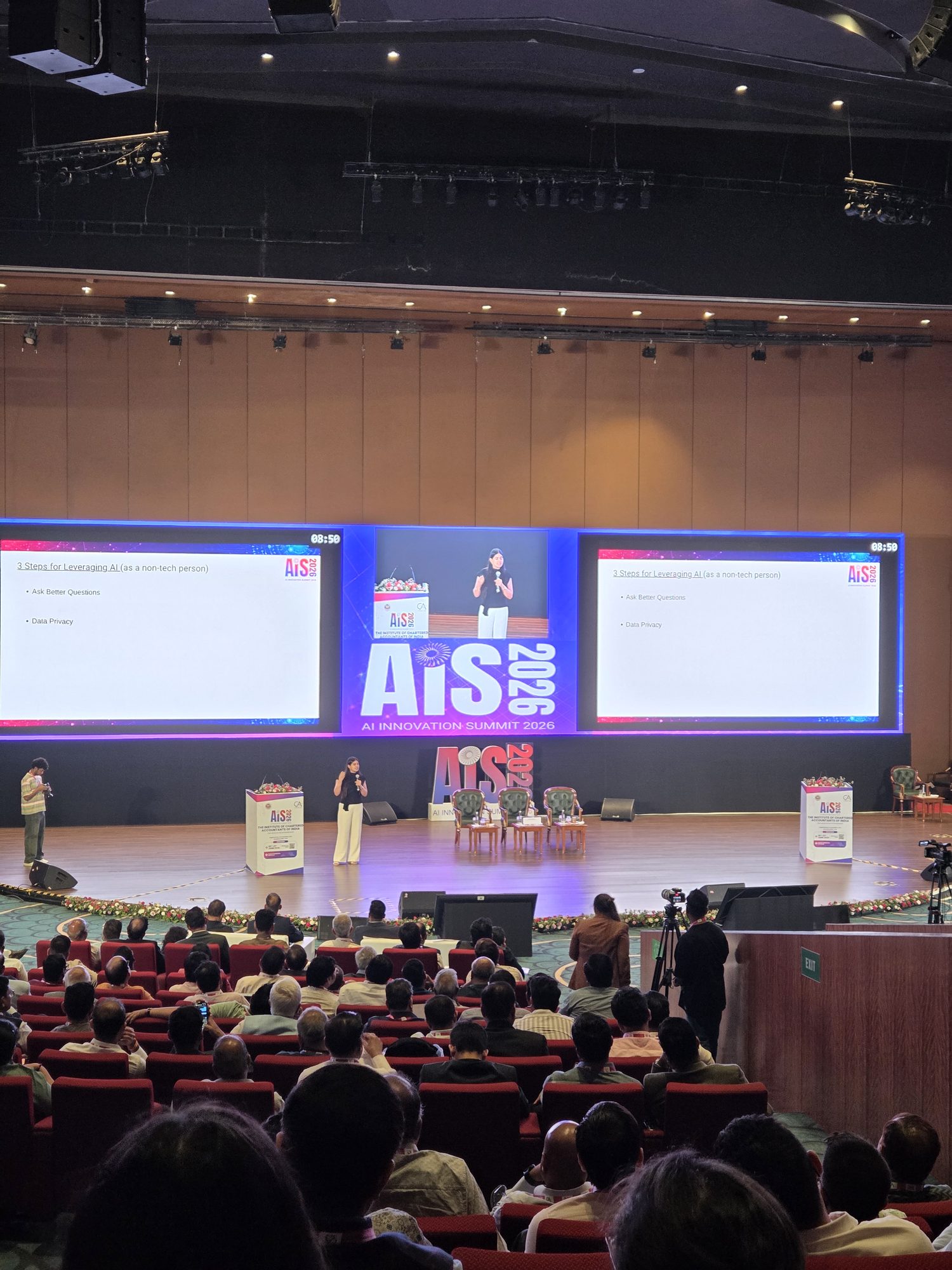 A keynote session at ICAI's AI Innovation Summit 2026, with a slide reading '3 Steps for Leveraging AI (as a non-tech person)' — Ask Better Questions and Data Privacy — visible behind the speaker, with a full audience of Chartered Accountants at Bharat Mandapam.